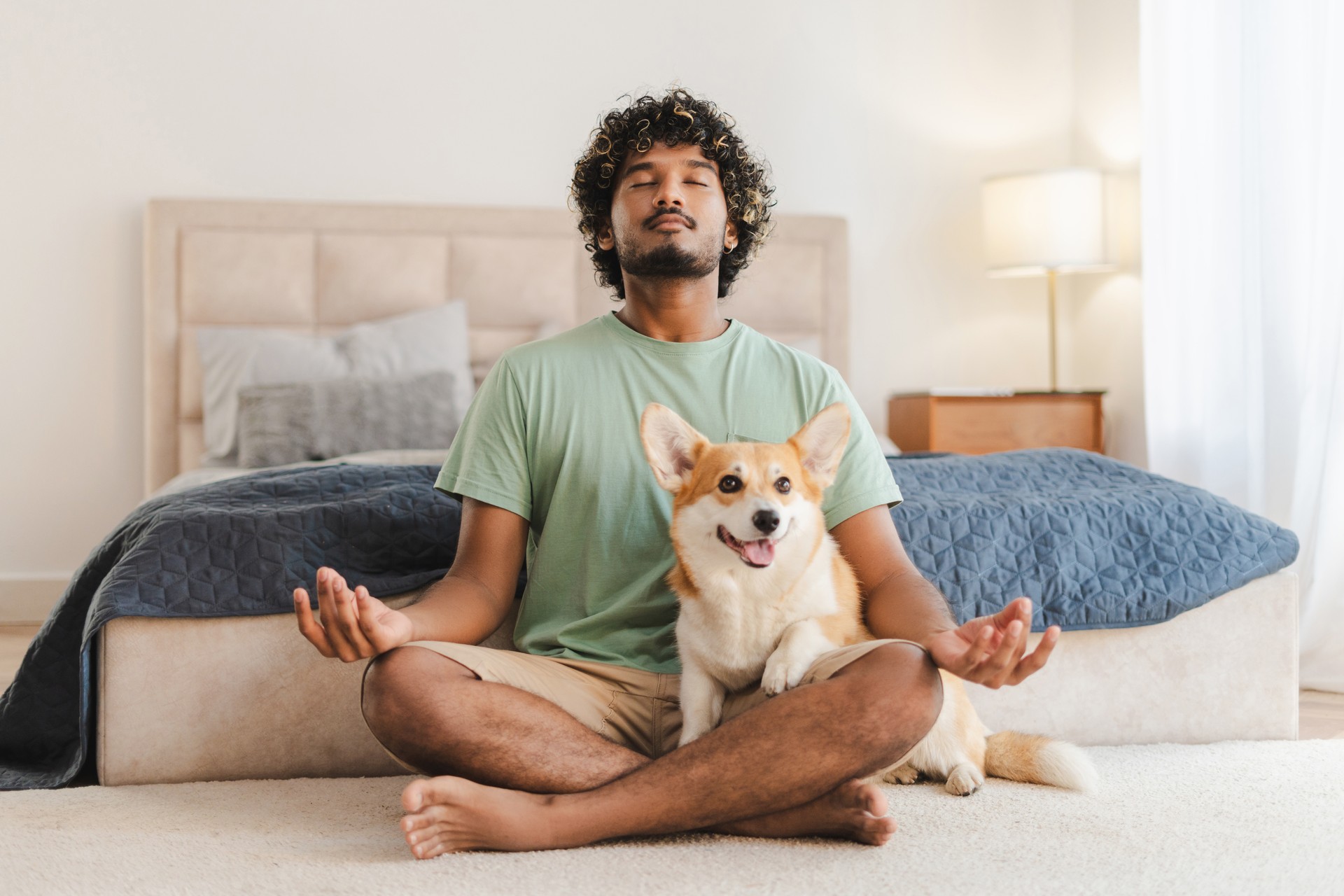 Indian man practicing yoga with dog sitting on lap at home