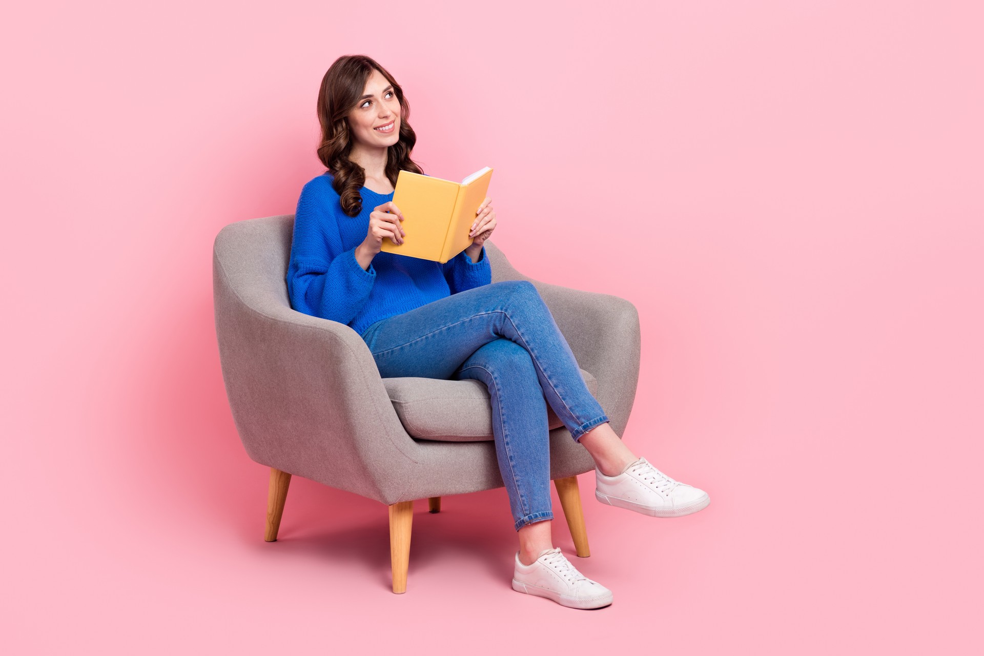 Full body photo of minded creative lady sit cozy chair hold opened book look empty space isolated on pink color background