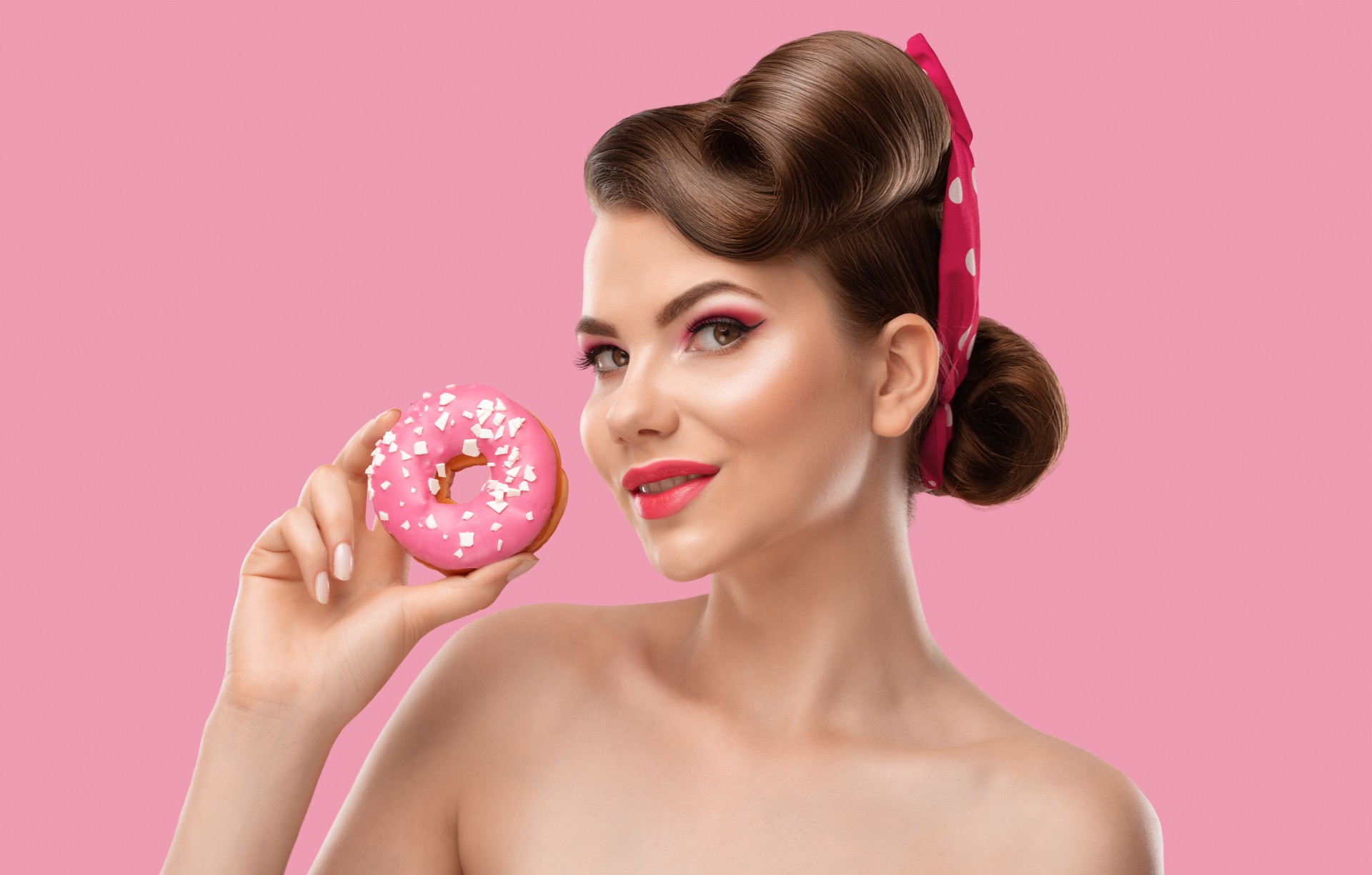 Young beautiful woman with hairstyle and bright makeup holds a donut with glaze in her hand. Professional makeup and facial care.