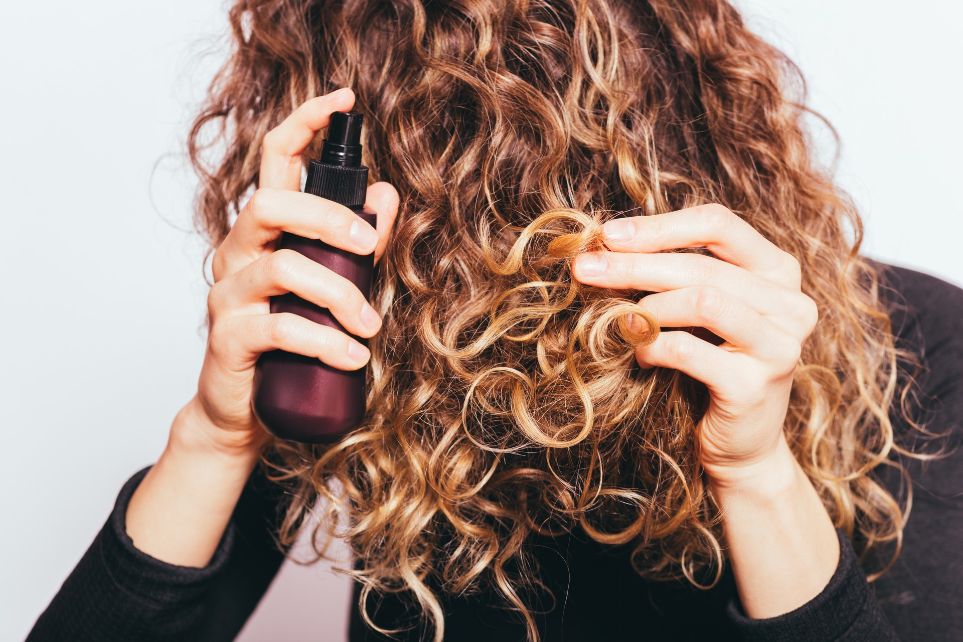 Close-up young woman spraying cosmetic oil