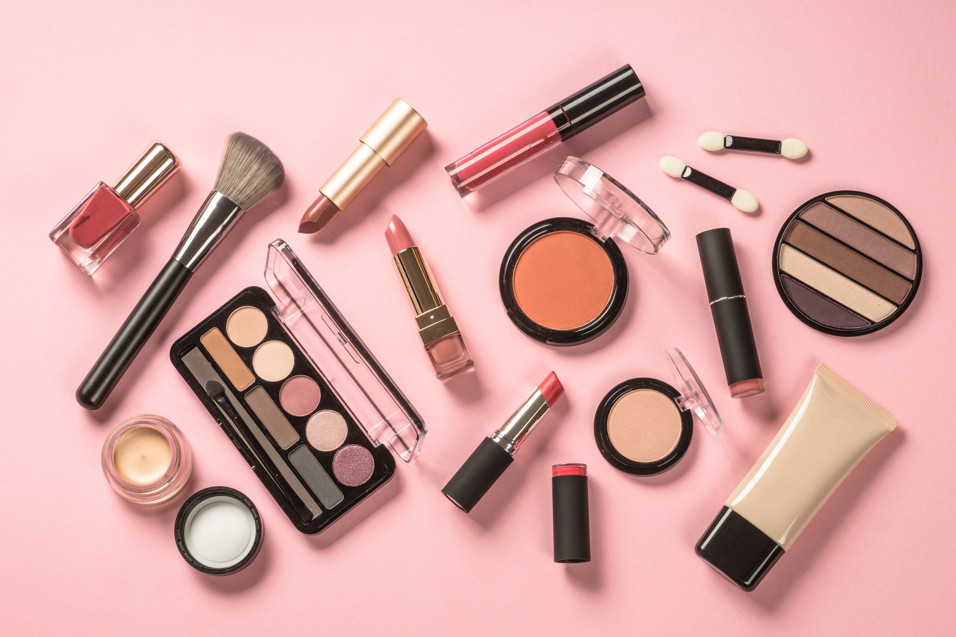 Make up products at pink background top view.