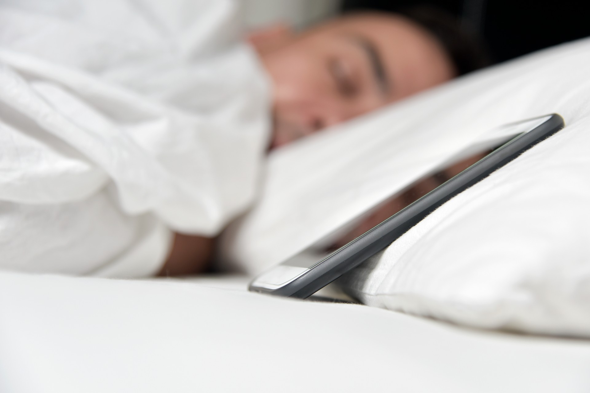 young man in bed close to his smartphone