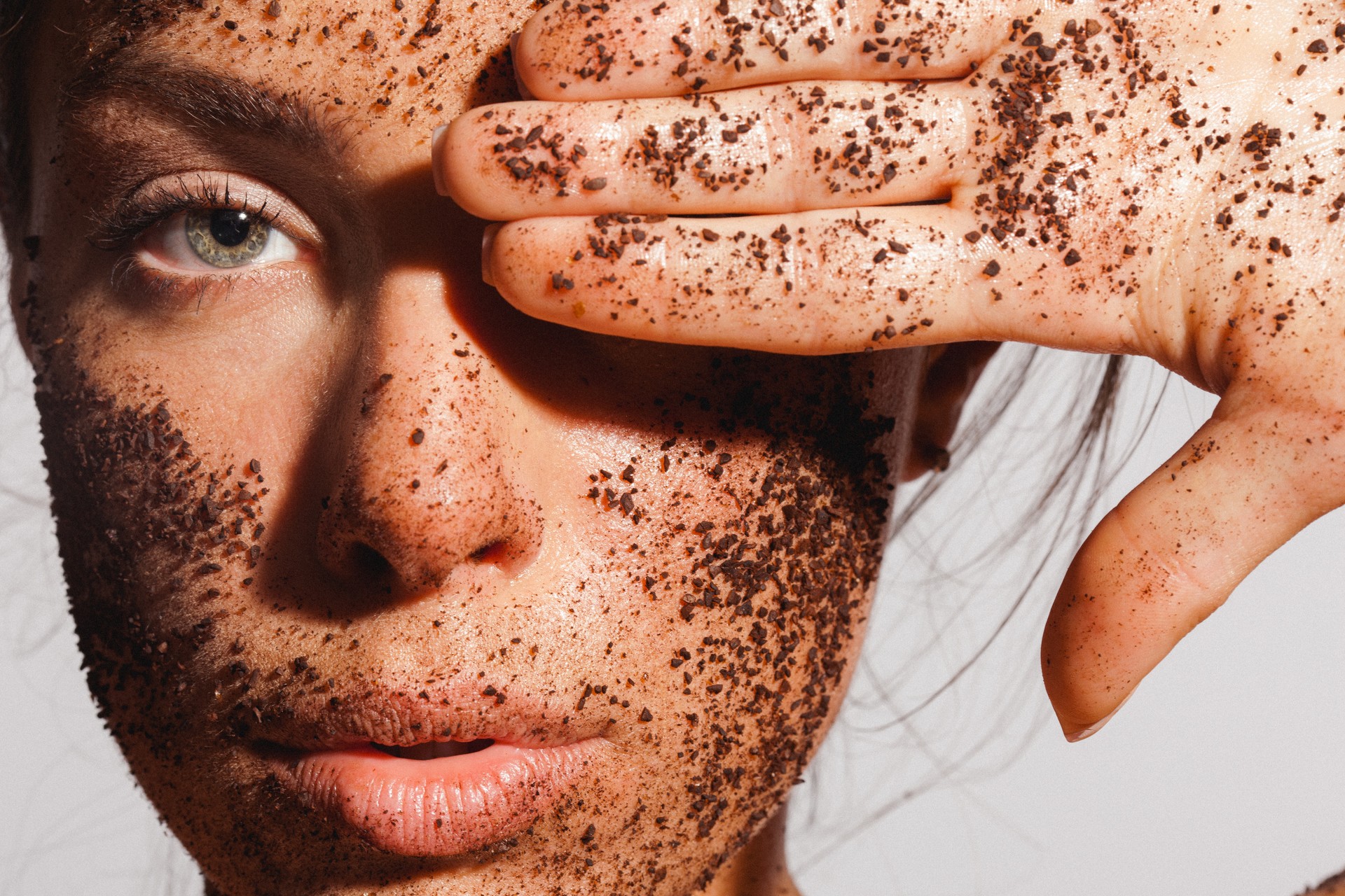 Beauty portrait of a young woman with ground coffee over her clean healthy skin