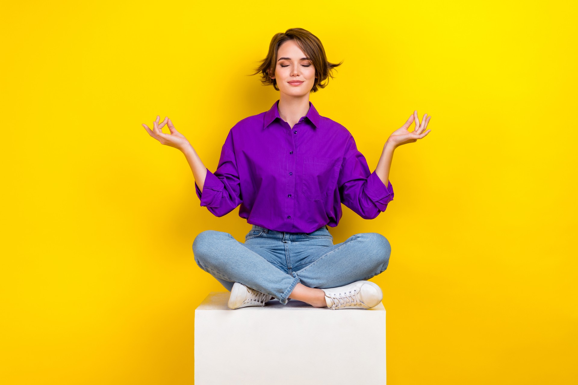 Full size portrait of calm pretty girl sit podium cube closed eyes meditate isolated on yellow color background